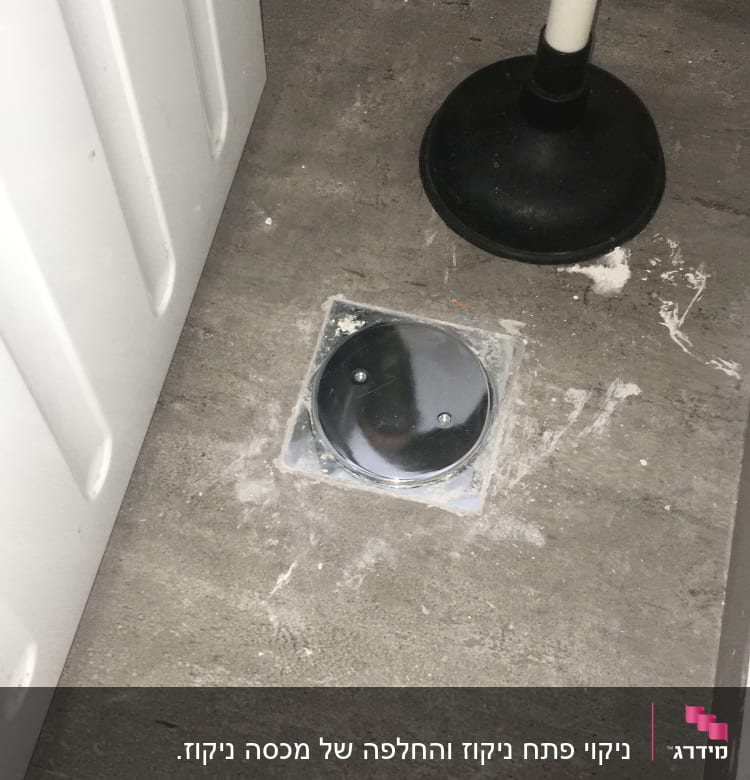 פומפה שחורה על רצפה ליד מכסה ניקוז מתכת